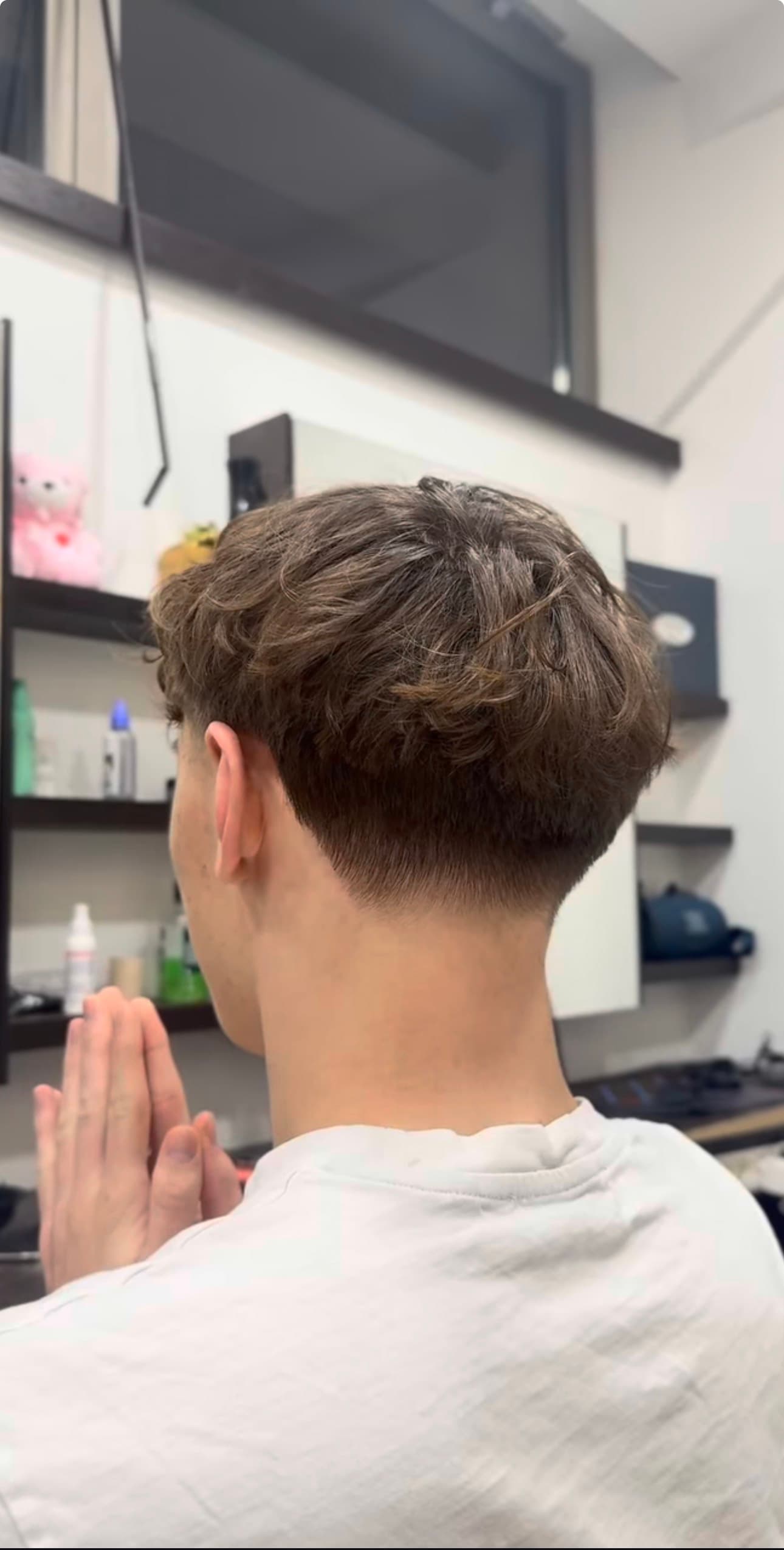 Rear view of a man's textured wavy crop haircut with a clean taper fade.